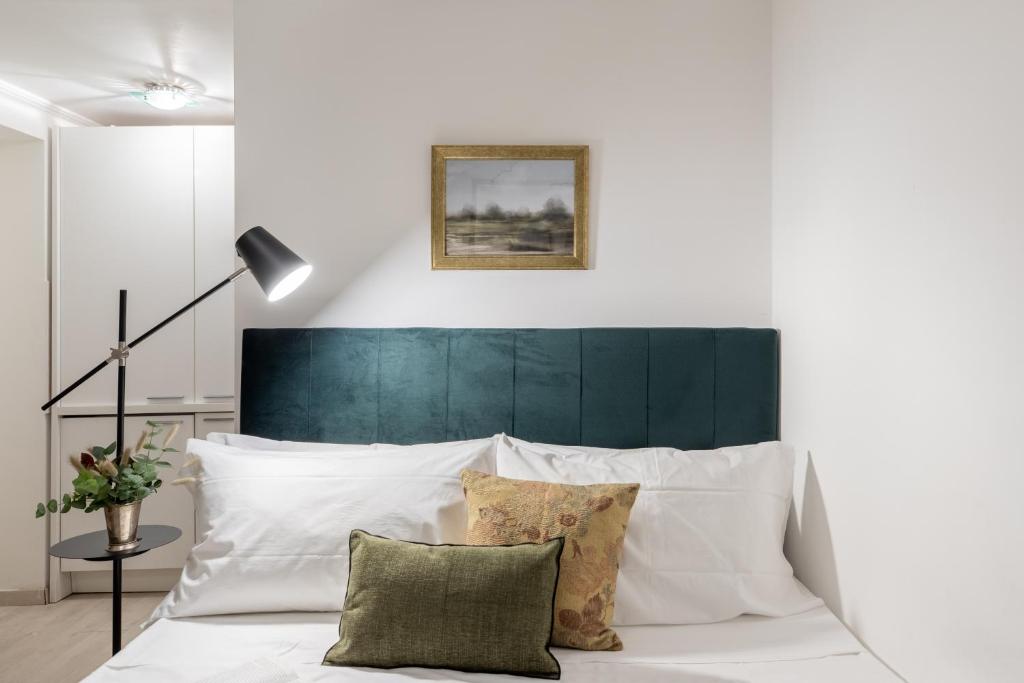 a white bed with a green headboard and pillows at Basic Studio - 350 m far from Fontana di Trevi in Rome