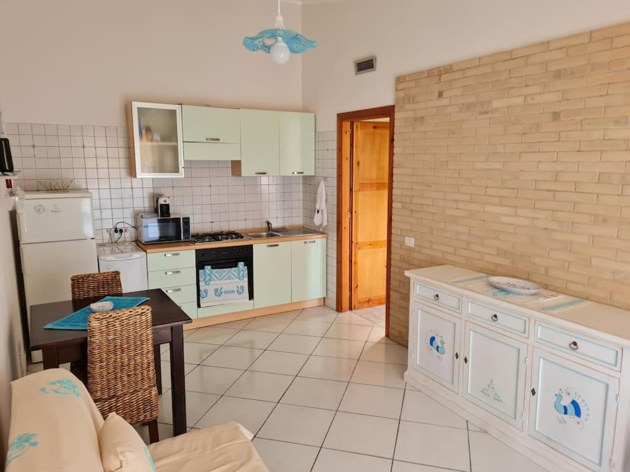 a kitchen with white cabinets and a table in it at Casa Alessandro in Villasimius