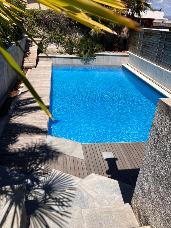 - une piscine dans une cour avec une terrasse en bois dans l'établissement 2 pièces rez-de-jardin dans maison avec piscine, à Villeneuve-Loubet