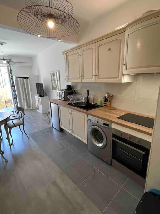 a kitchen with white cabinets and a washer and dryer at Appartement atypique et original in Nice