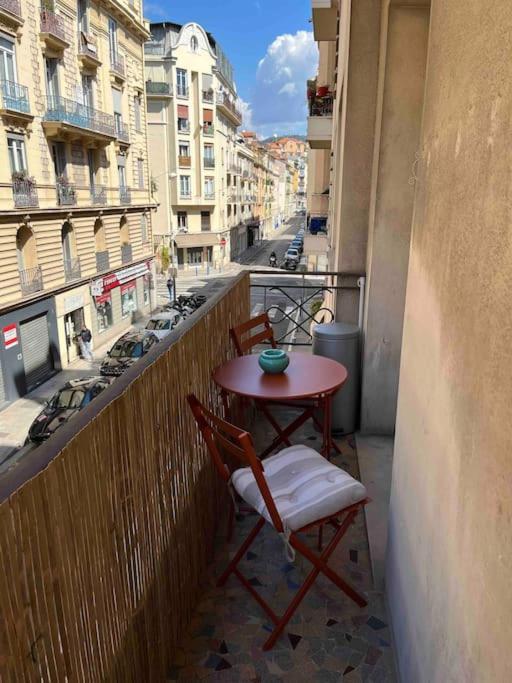 a table and chairs on a balcony with a view of a city at Appartement atypique et original in Nice
