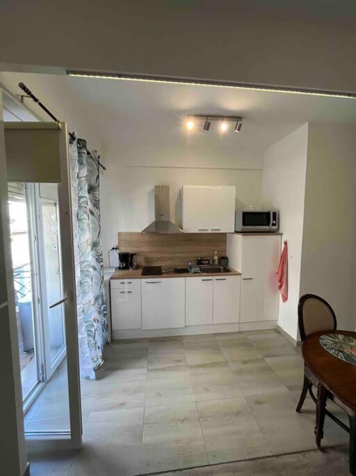 a kitchen with white cabinets and a table in a room at Appartement atypique et original in Nice