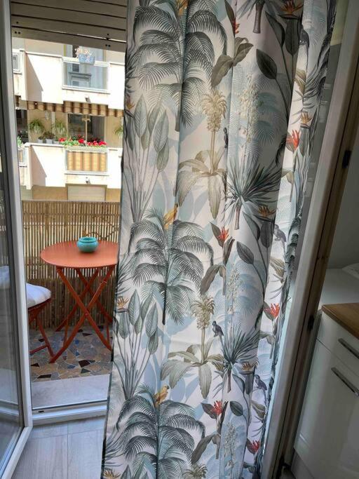 a curtain in a room with a table and a window at Appartement atypique et original in Nice
