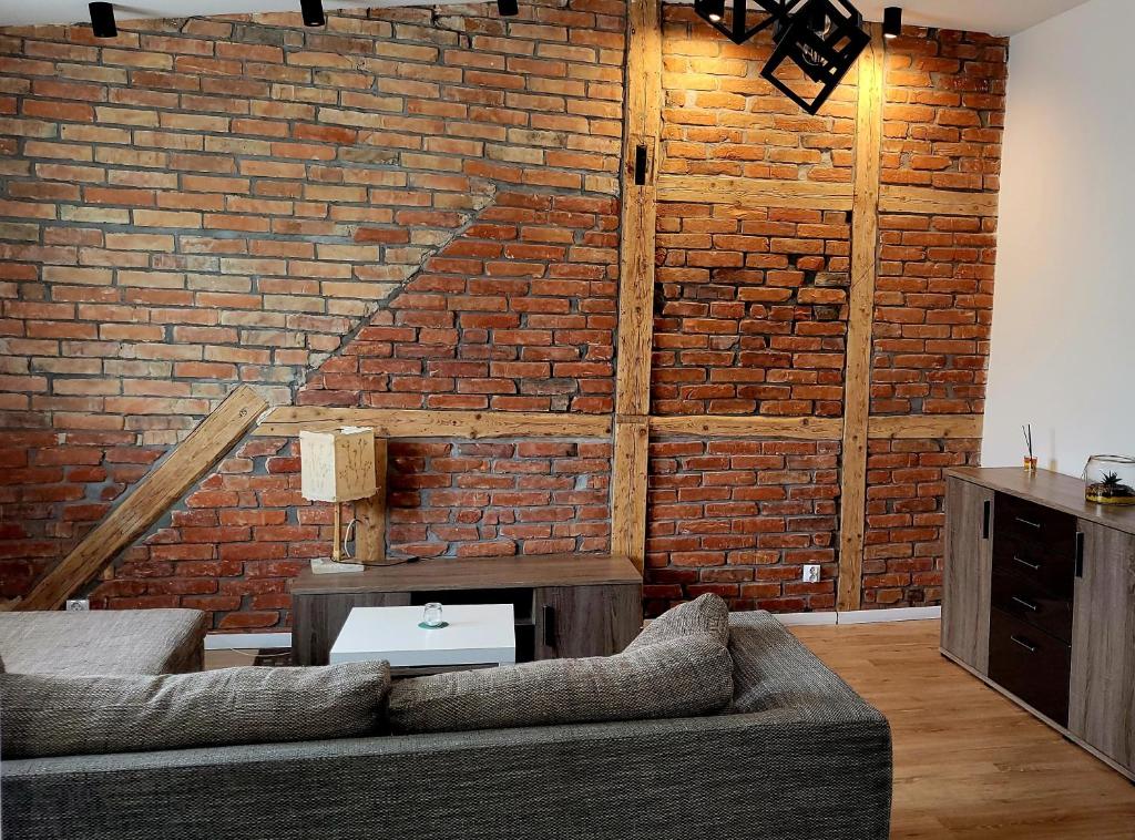 a living room with a brick wall and a couch at Przytulny Apartament w centrum miasta in Kętrzyn