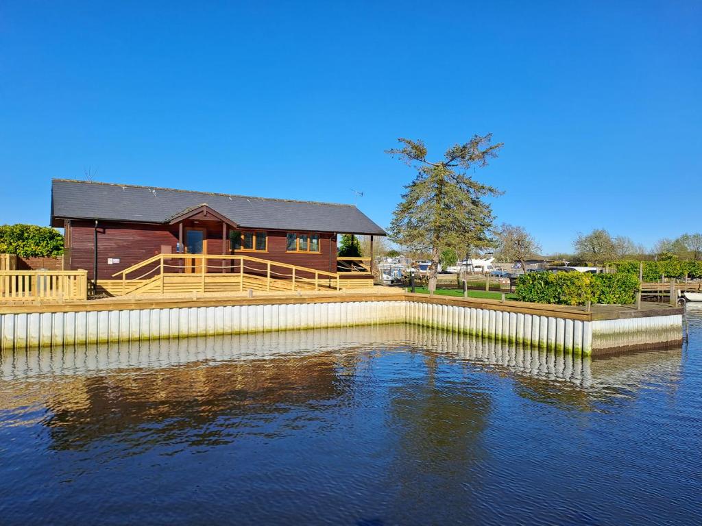 a house with a dock next to a body of water at River Rest - Norfolk Broads in Brundall