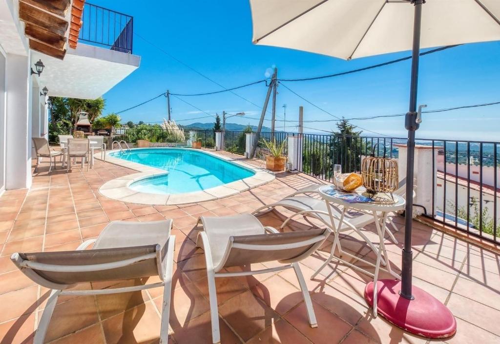 eine Terrasse mit einem Tisch, Stühlen und einem Pool in der Unterkunft Costacabana - Villa Sofia in Lloret de Mar