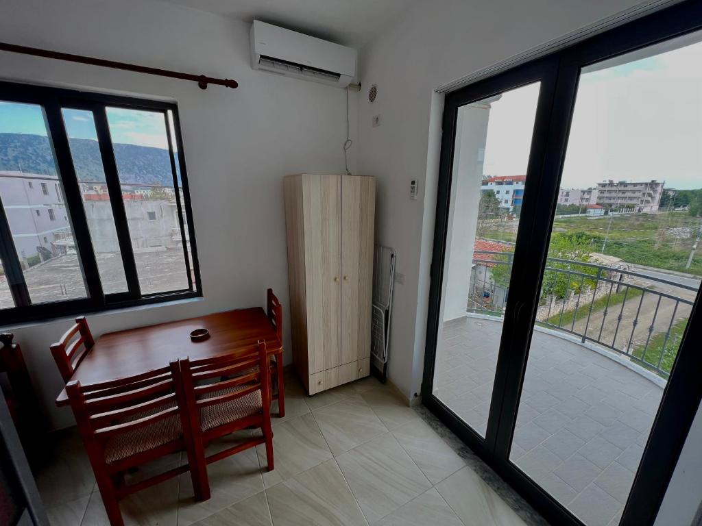 Habitación con mesa y balcón con ventanas. en Sar Hotel, Velipojë en Velipojë