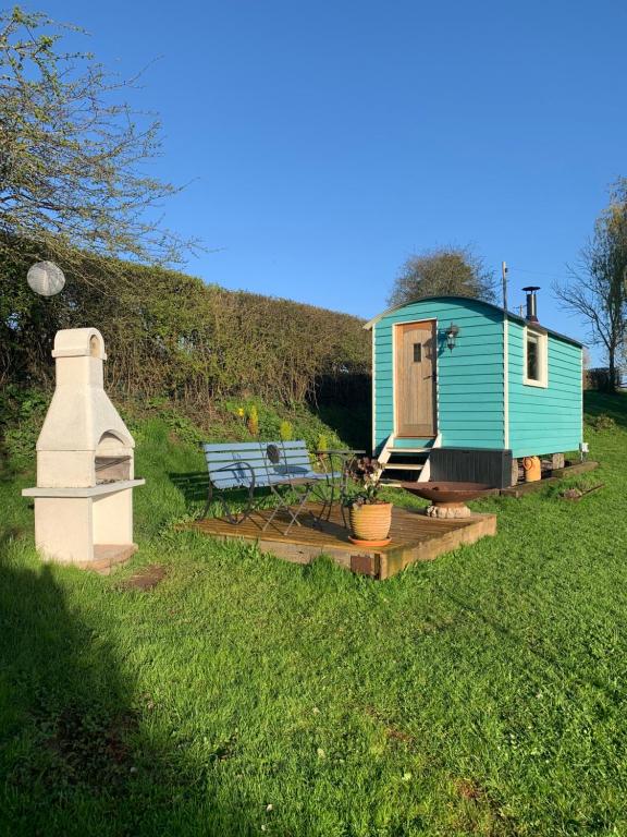 een blauw tiny house met een bank en een tafel bij The Gannah Farm Shepherds Hut in Hereford