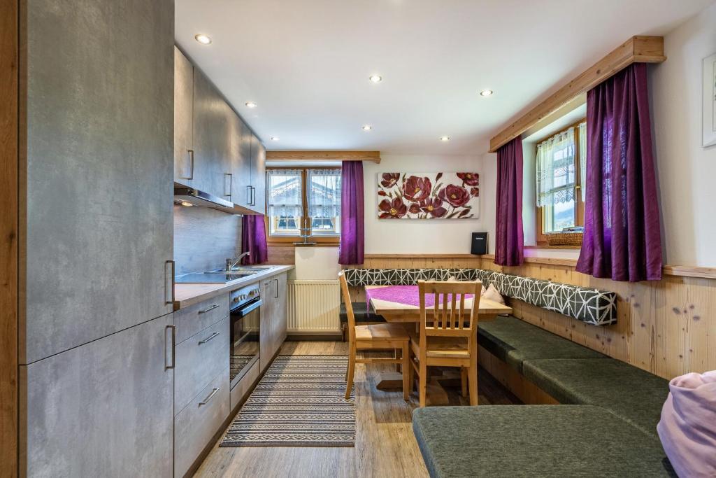 a kitchen with purple curtains and a table and chairs at Unterlehenhof A in Zell am Ziller