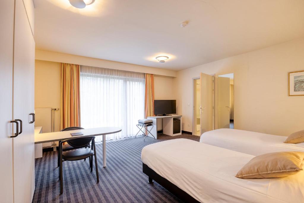 a hotel room with two beds and a desk at Priorij Corsendonk in Oud-Turnhout
