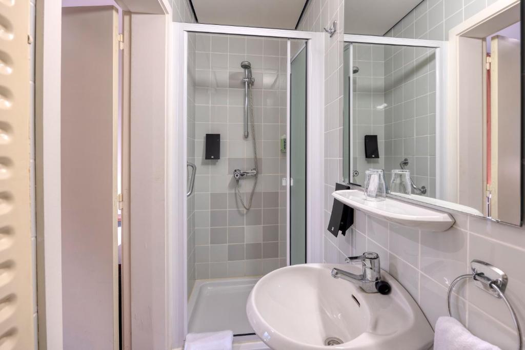 a white bathroom with a shower and a sink at Priorij Corsendonk in Oud-Turnhout