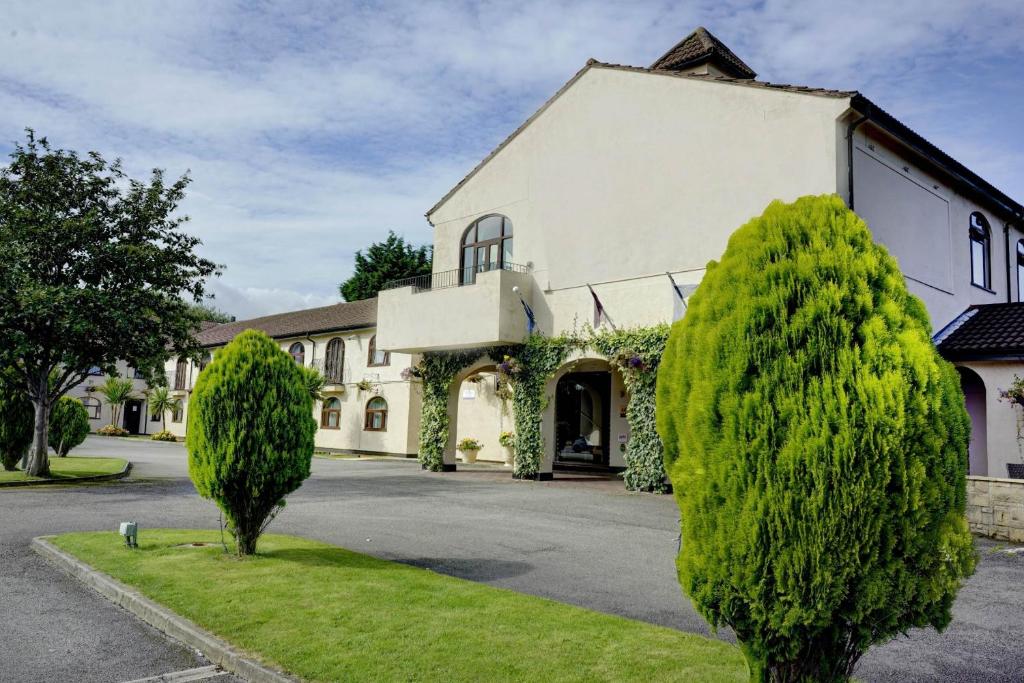 a large white building with trees in front of it at Widnes Halton Everglades Park Hotel in Widnes