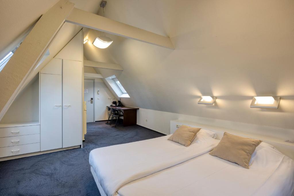 a attic bedroom with two beds and a desk at Priorij Corsendonk in Oud-Turnhout