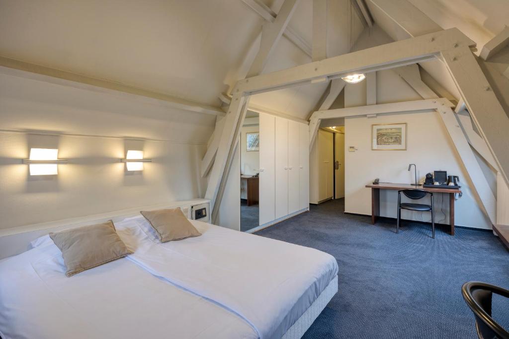 a bedroom with a large white bed and a desk at Priorij Corsendonk in Oud-Turnhout