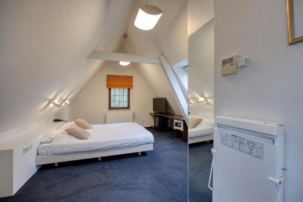 a bedroom with a bed and a desk in a attic at Priorij Corsendonk in Oud-Turnhout