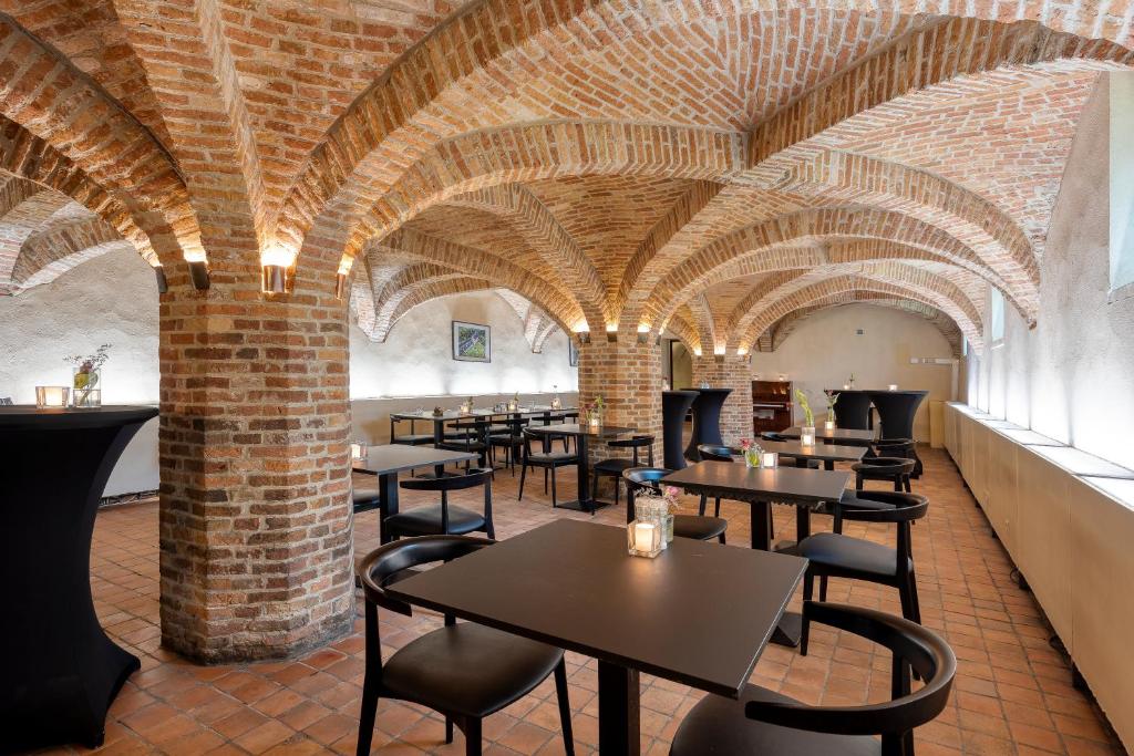 a restaurant with brick walls and tables and chairs at Priorij Corsendonk in Oud-Turnhout