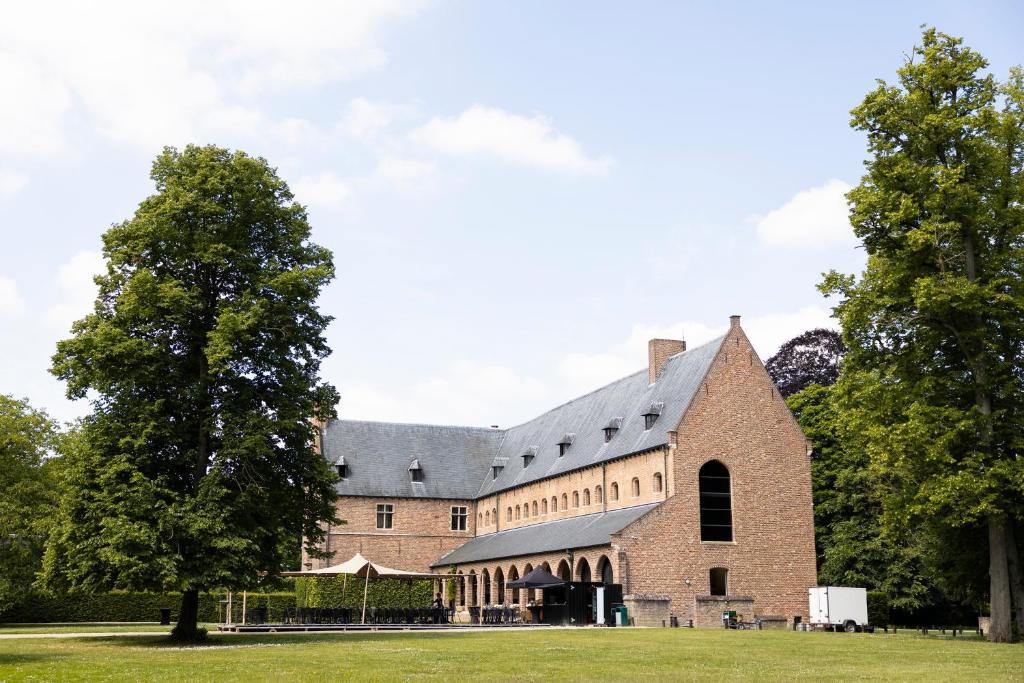 a large brick building with a tree in the foreground at Priorij Corsendonk in Oud-Turnhout