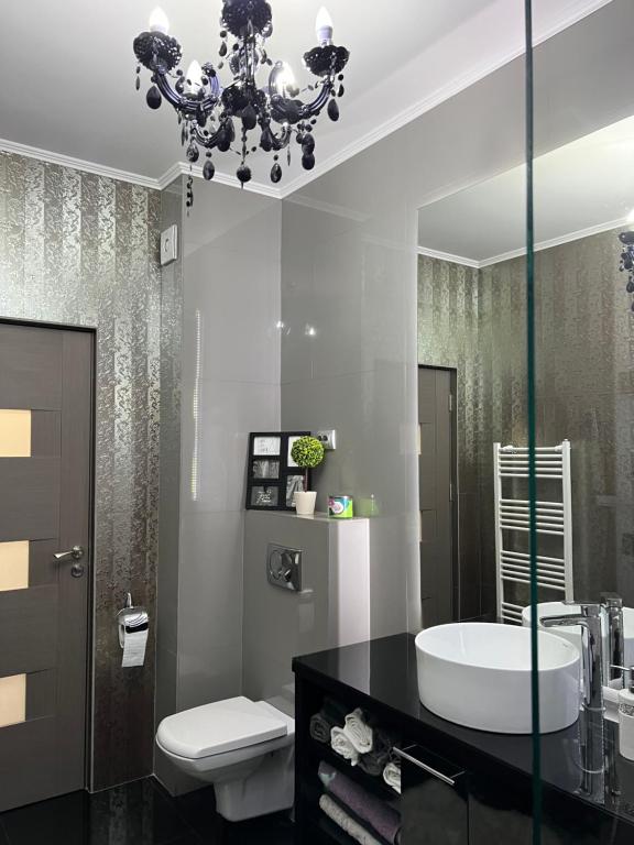 a bathroom with a sink and a toilet and a chandelier at Luxurious Accommodation in Floreşti