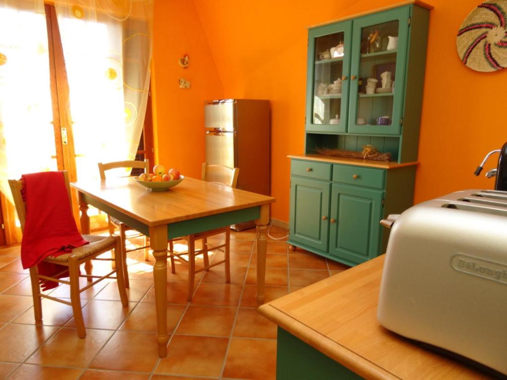 cocina con armarios verdes, mesa y nevera en BB DoliaHouse en Dolianova