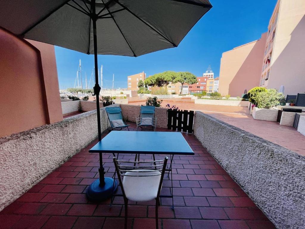 une table et des chaises avec un parasol sur une terrasse dans l'établissement Bel appartement 4 pers, centre-port, proche plage – Cap d'Agde - FR-1-723-60, au Cap d'Agde