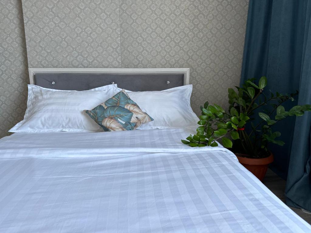 uma cama branca com duas almofadas e uma planta em ExpoNewLife2 em Astana