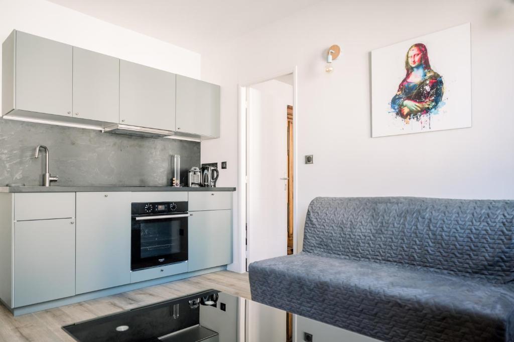 a kitchen with white cabinets and a couch in it at Le Saint Amans in Rodez