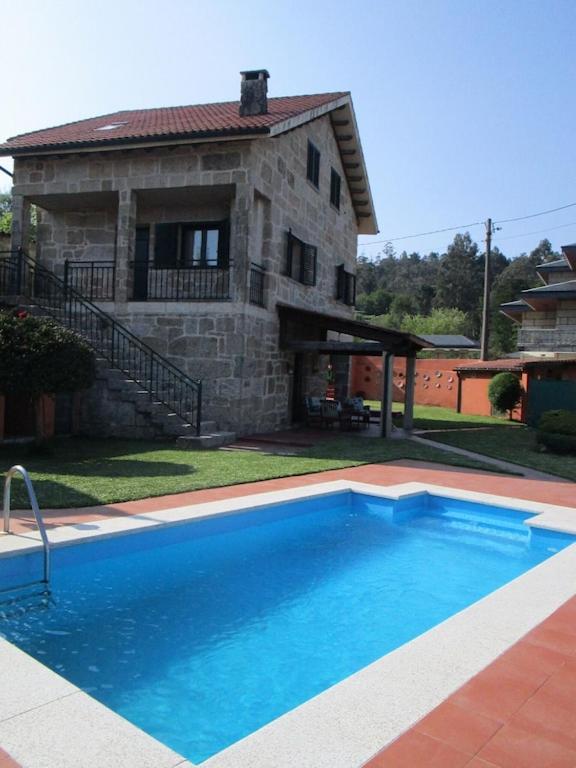 a large blue swimming pool in front of a house at La Cabadachan in Vilaboa