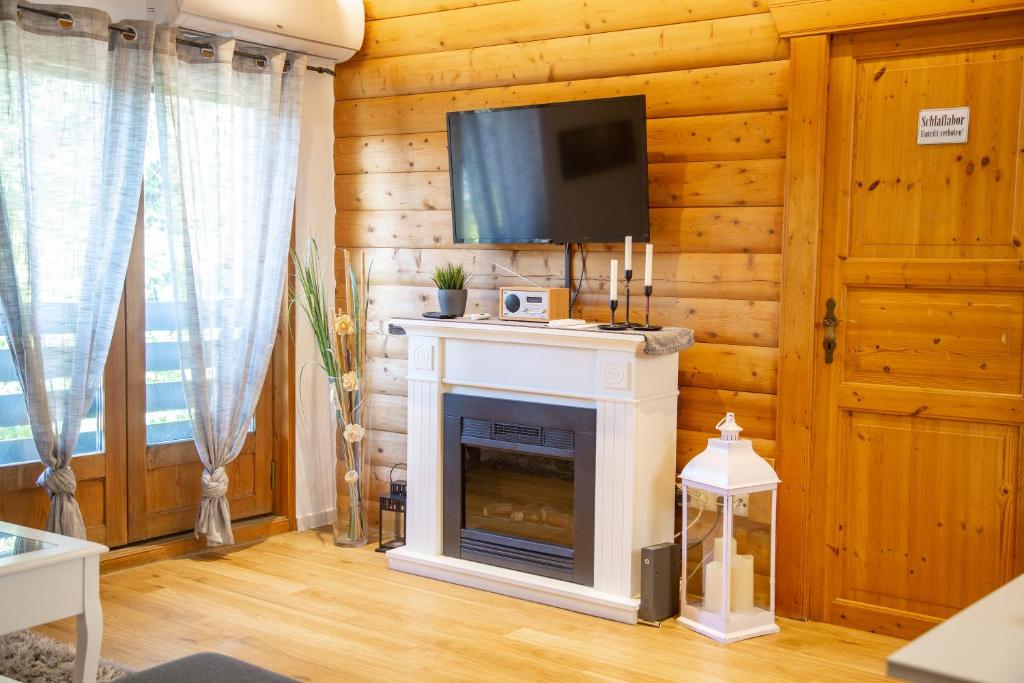 a living room with a fireplace and a flat screen tv at Moorhütte in Isenbüttel