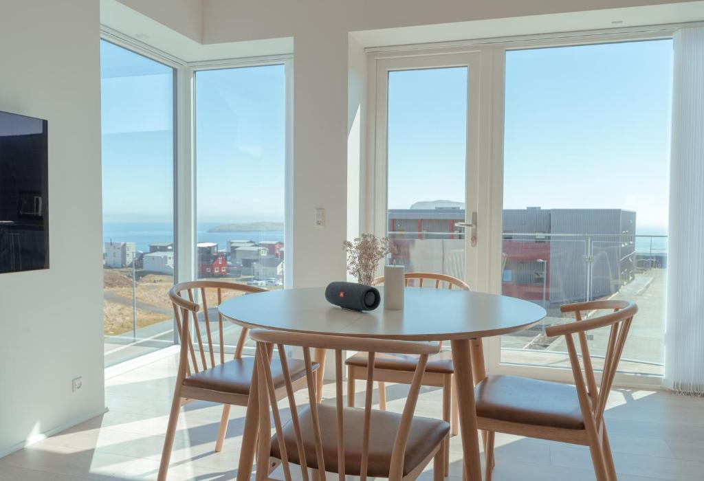 comedor con mesa, sillas y ventanas en New 2 Bedroom Apartment With Sea View en Tórshavn
