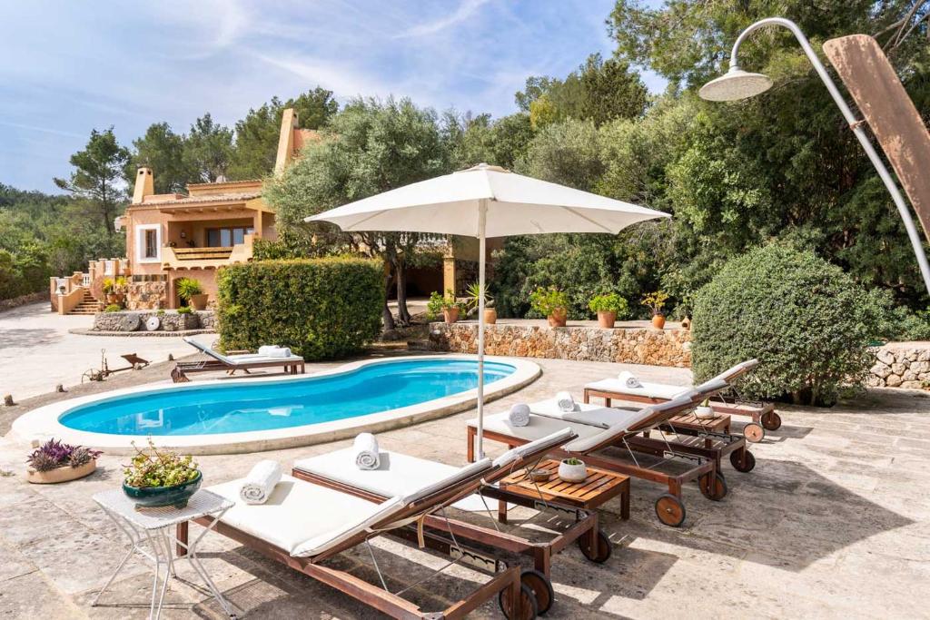 a pool with chairs and an umbrella next to a house at Lovehaus Terra Rotja in Esporles