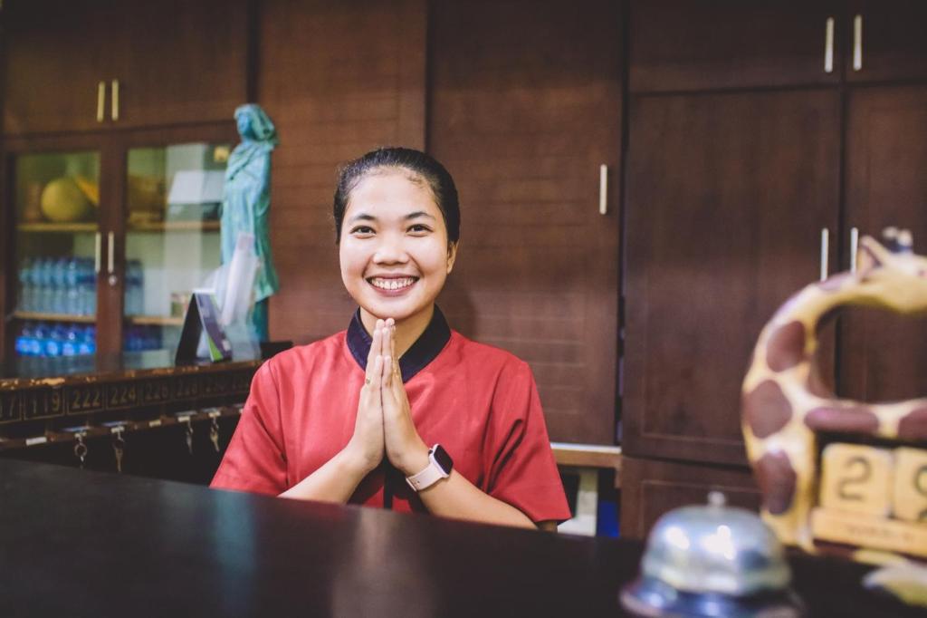 uma mulher sentada numa mesa com as mãos para cima em PIA Hotel Medan em Medan