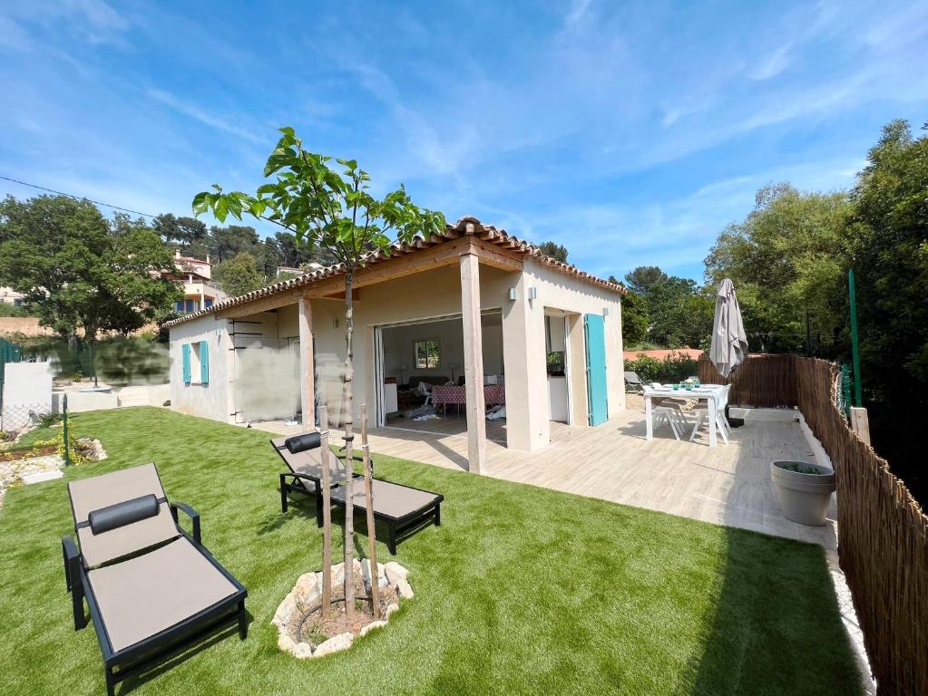 a backyard with a table and chairs on the grass at Maisonnette avec 2 chambres climatisée en face de la plage de Gigaro in La Croix-Valmer