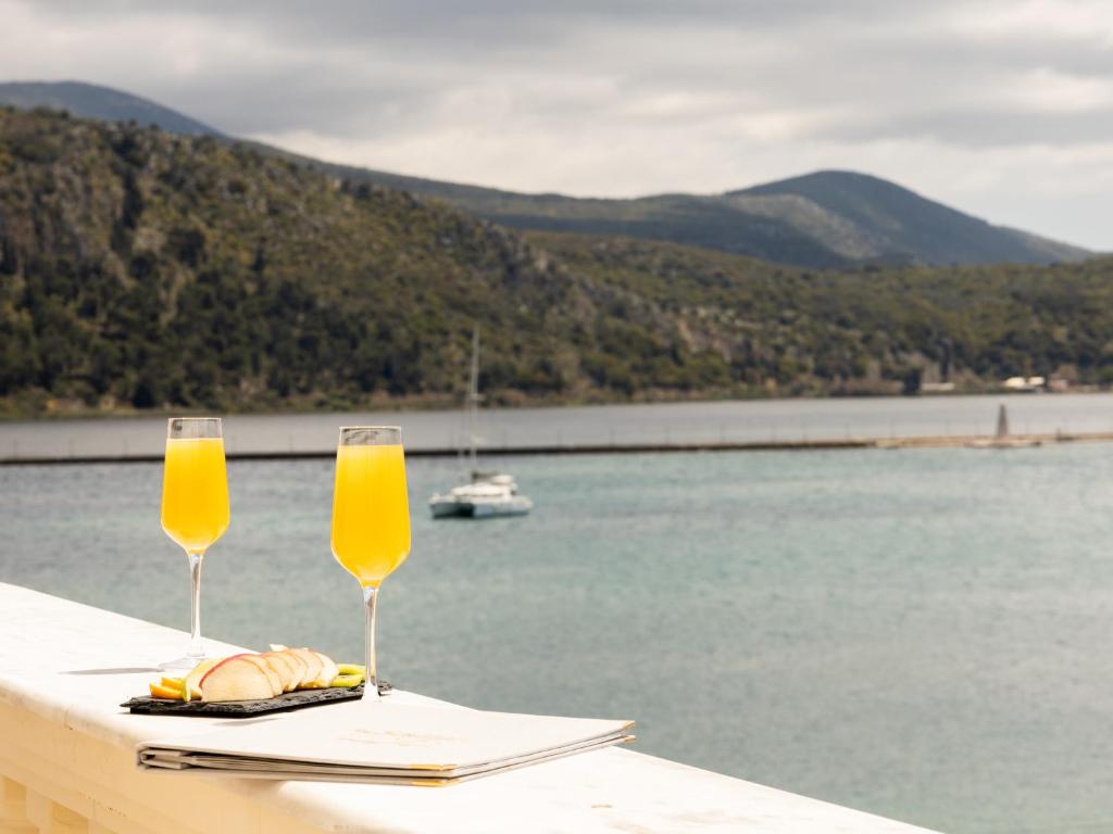 two glasses of orange juice on a table next to the water at Alley Boutique Hotel and Spa in Argostoli