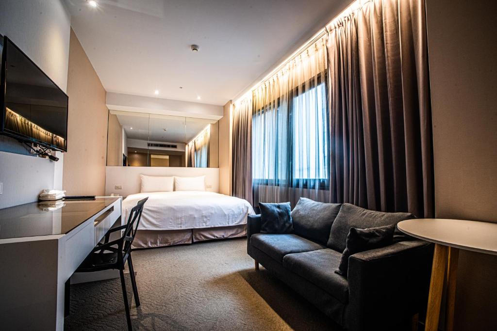 um quarto de hotel com uma cama e um sofá em Artinn藝築文旅-台北站前館 em Taipei