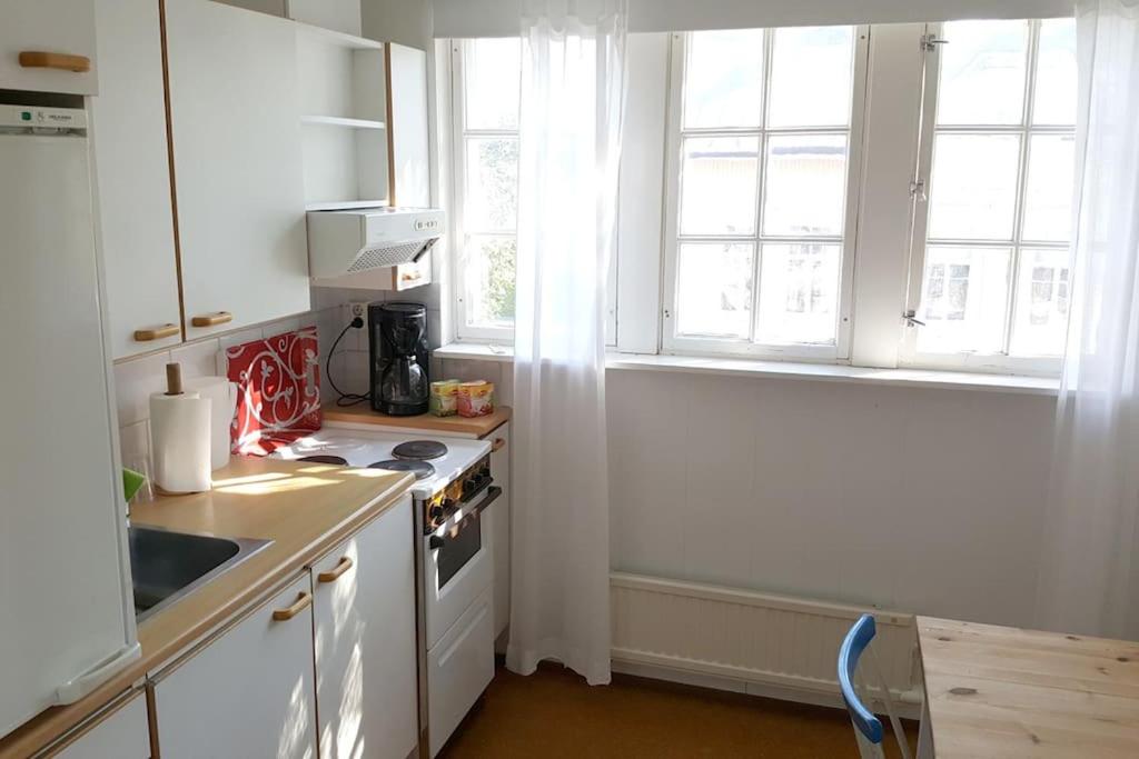 a kitchen with white cabinets and a stove and windows at Vindsvåning, stenkast från centrum in Pietarsaari