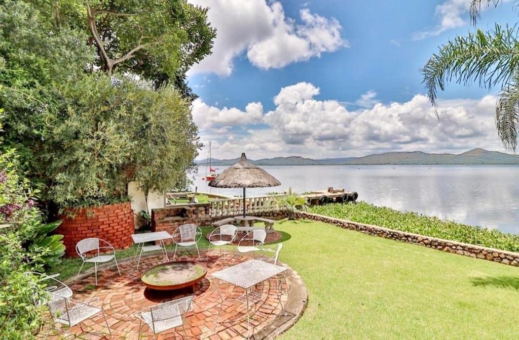 a patio with chairs and an umbrella and a body of water at 147@ Simon Bekker Kosmos in Hartbeespoort