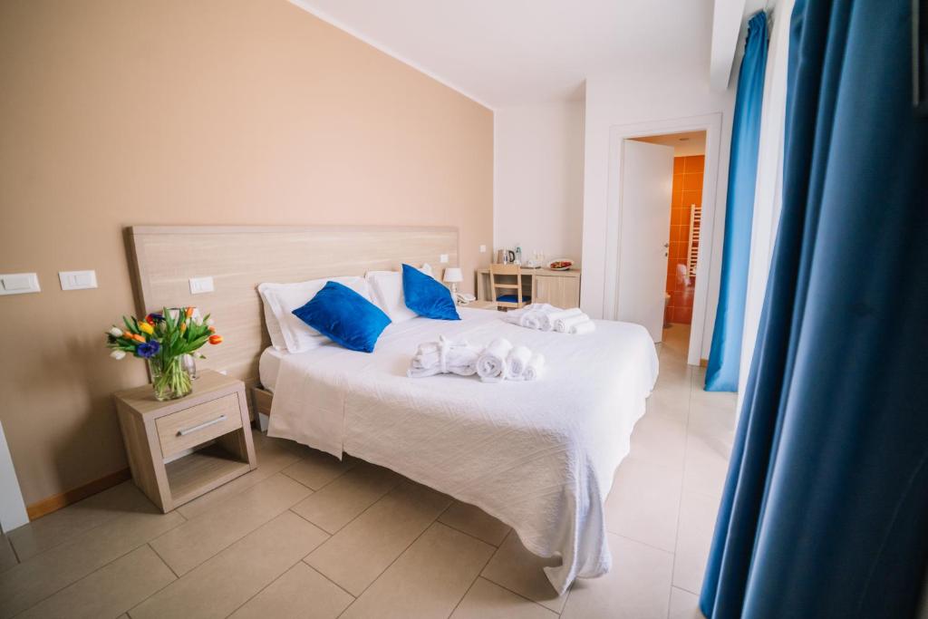 a bedroom with a white bed with blue pillows at Hotel Villa Sveva in Cagliari