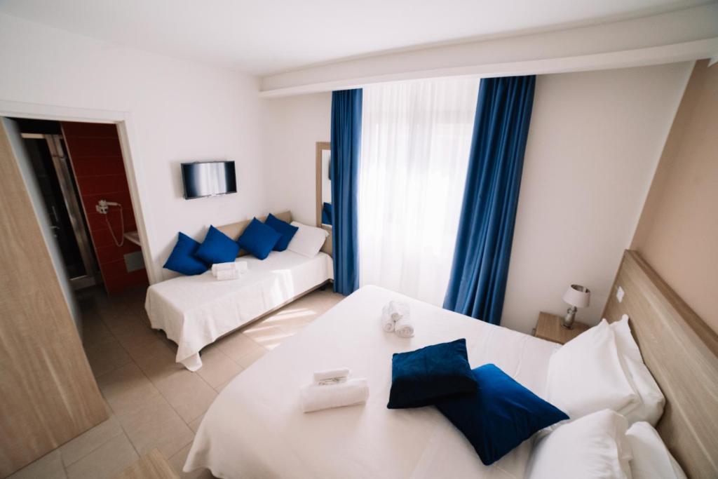a hotel room with two beds and blue pillows at Hotel Villa Sveva in Cagliari