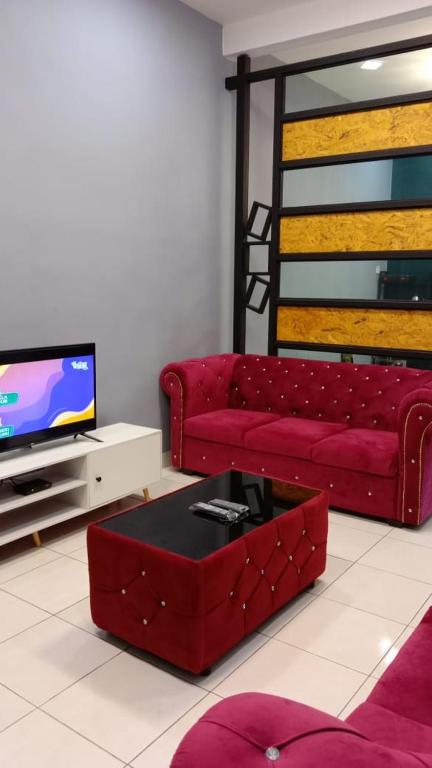a living room with a red couch and a tv at MAS'homestay perlis in Kangar