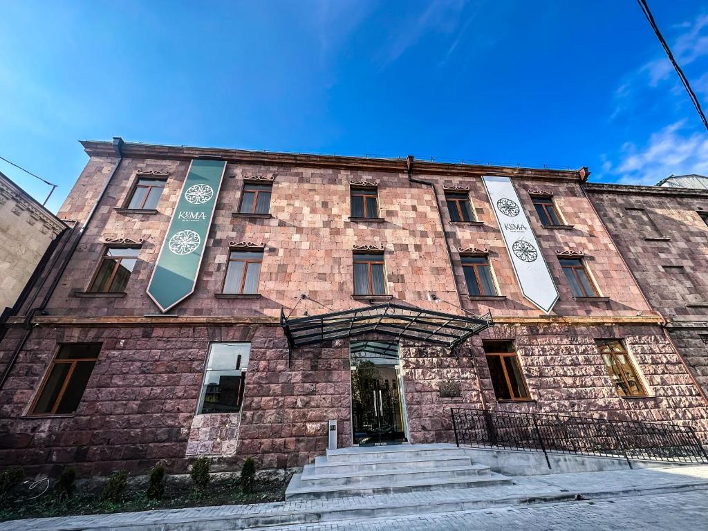 un gran edificio de ladrillo con dos letreros. en KUMA Hotel Gyumri en Gyumri