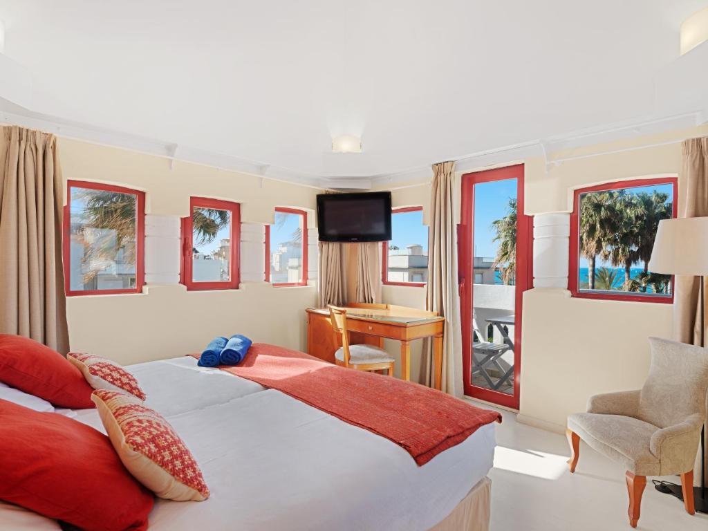 a hotel room with a bed and a desk and windows at Hotel Ciutat Jardi in Palma de Mallorca