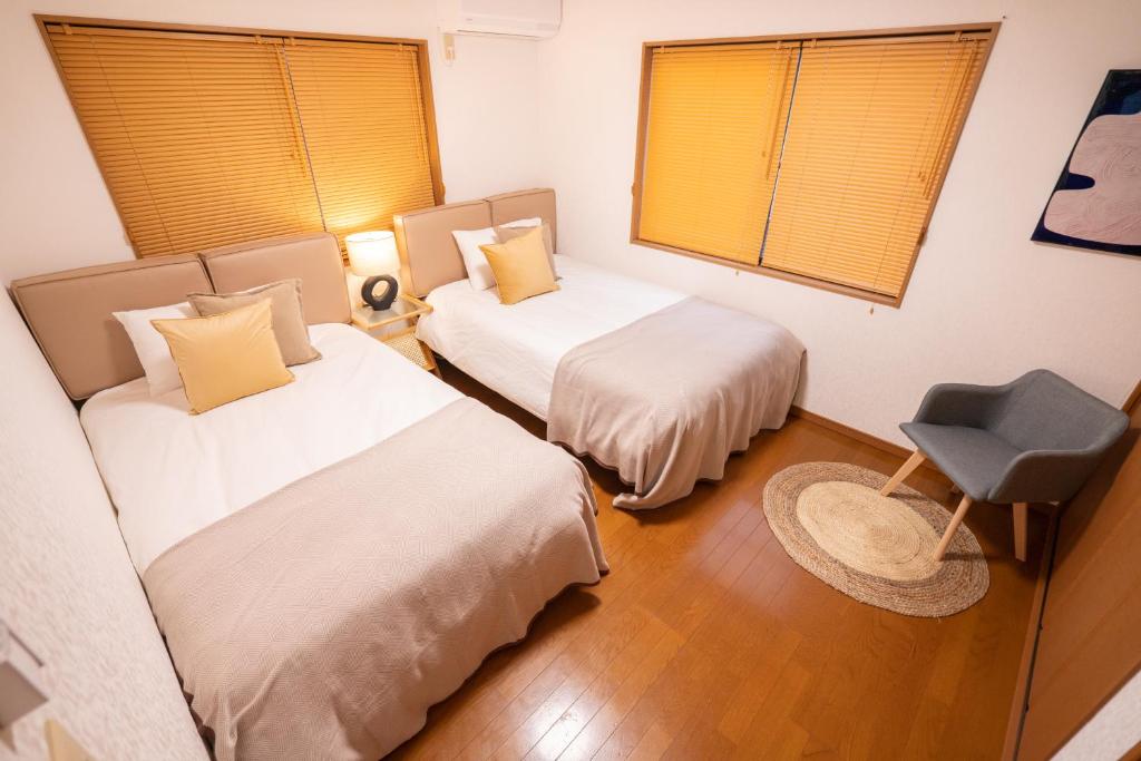 Cette chambre comprend 2 lits et une chaise. dans l'établissement HANAMIKAKU-shinjuku/akihabara/asakusa/ginza/tokyo/narita/haneta Japanese House 100㎡, à Tokyo