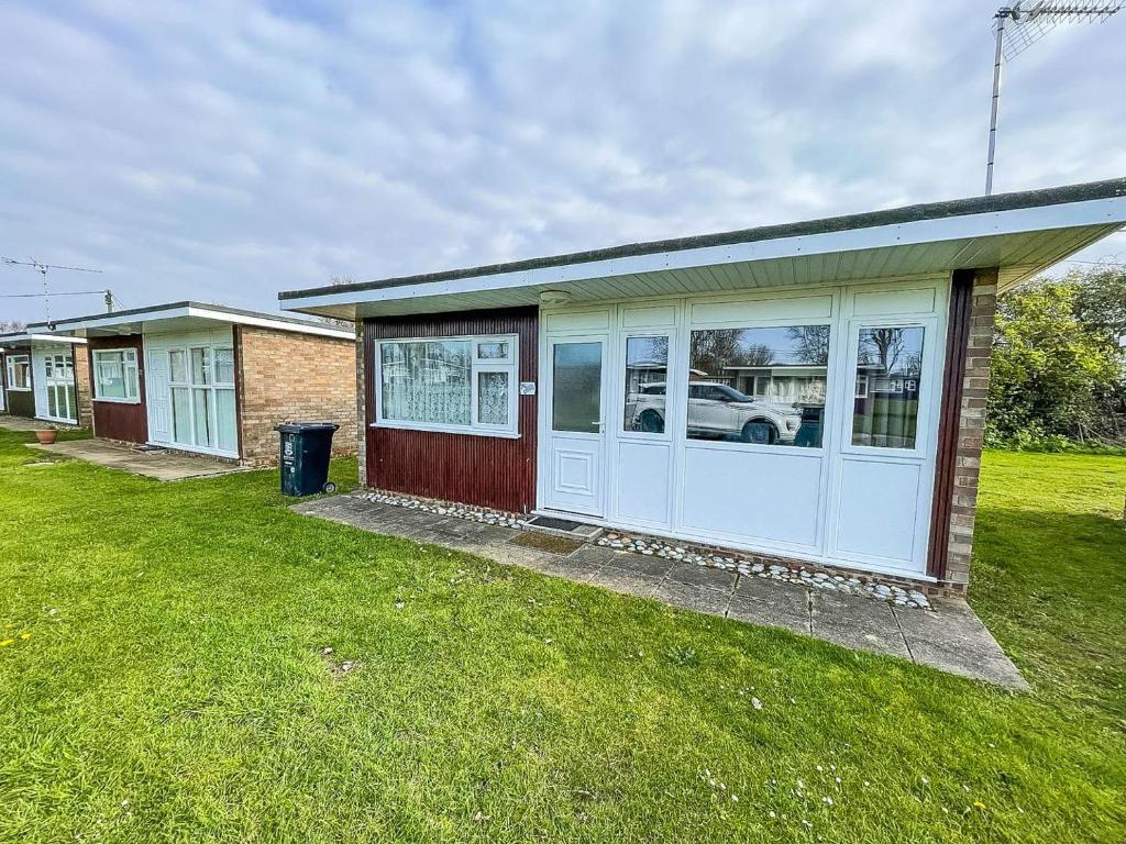 a house with a garage with a grass yard at Beautiful Chalet With Free Wifi Nearby Hemsby Beach In Norfolk Ref 59096s in Hemsby