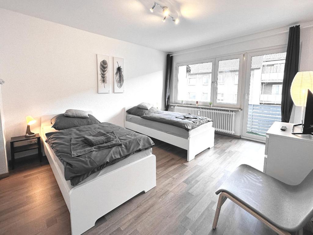 a bedroom with two beds and a desk and a chair at # VAZ Apartments RS04 Küche, TV, WLAN, Balkon in Remscheid