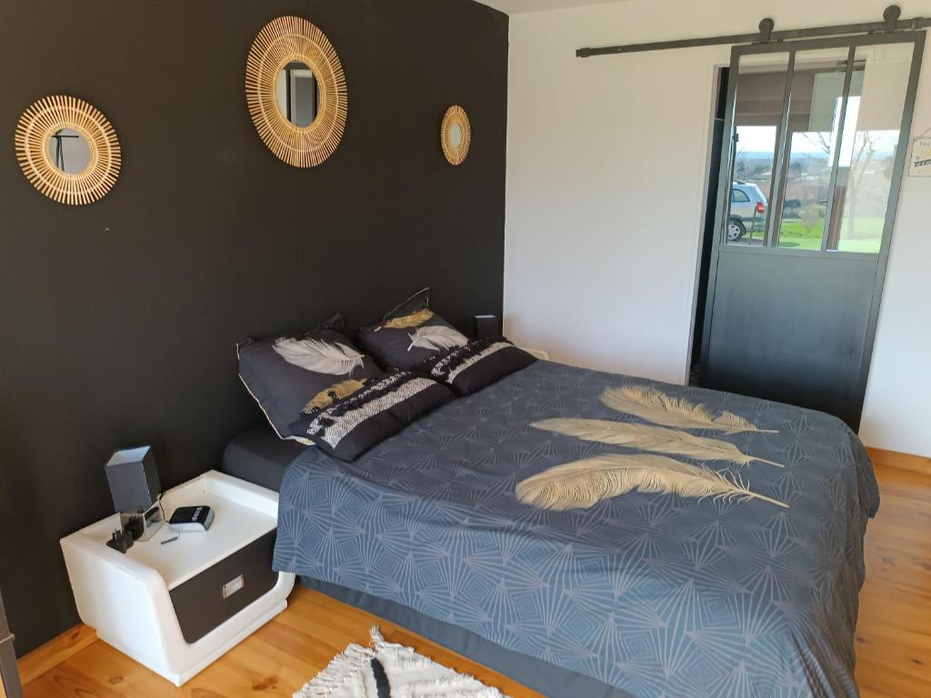 een slaapkamer met een bed met een blauw dekbed bij L'Eden in Tonneins