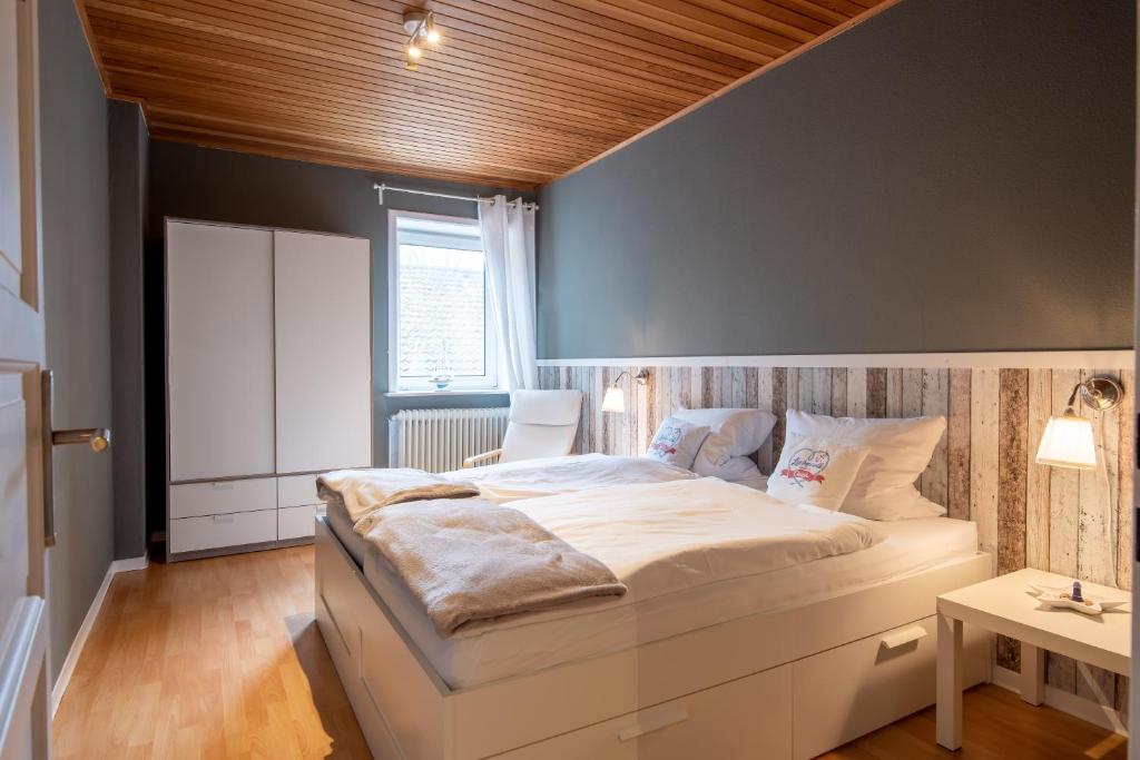 a bedroom with a large white bed with a wooden ceiling at Liebevoll hinterm Deich - Ferienwohnungen in Lehe