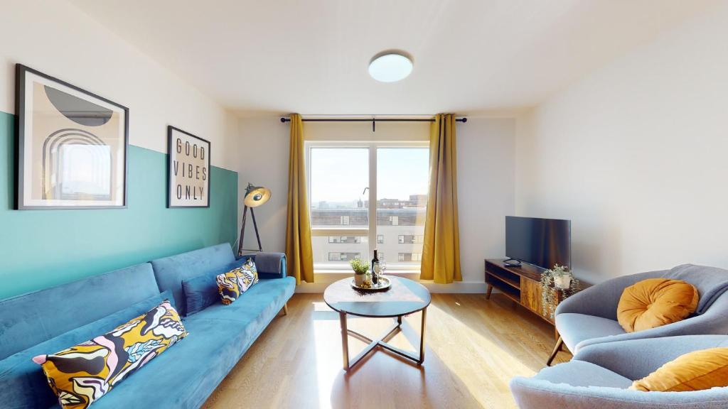 a living room with a blue couch and a table at Water View Apartment- 2 Bed - Cardiff Bay - Free Parking!! in Cardiff