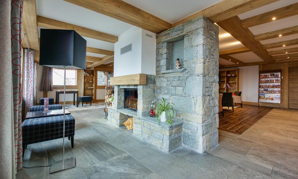 a living room with a stone fireplace and a tv at CGH Résidences &amp; Spas Chalet Les Marmottons in La Rosière