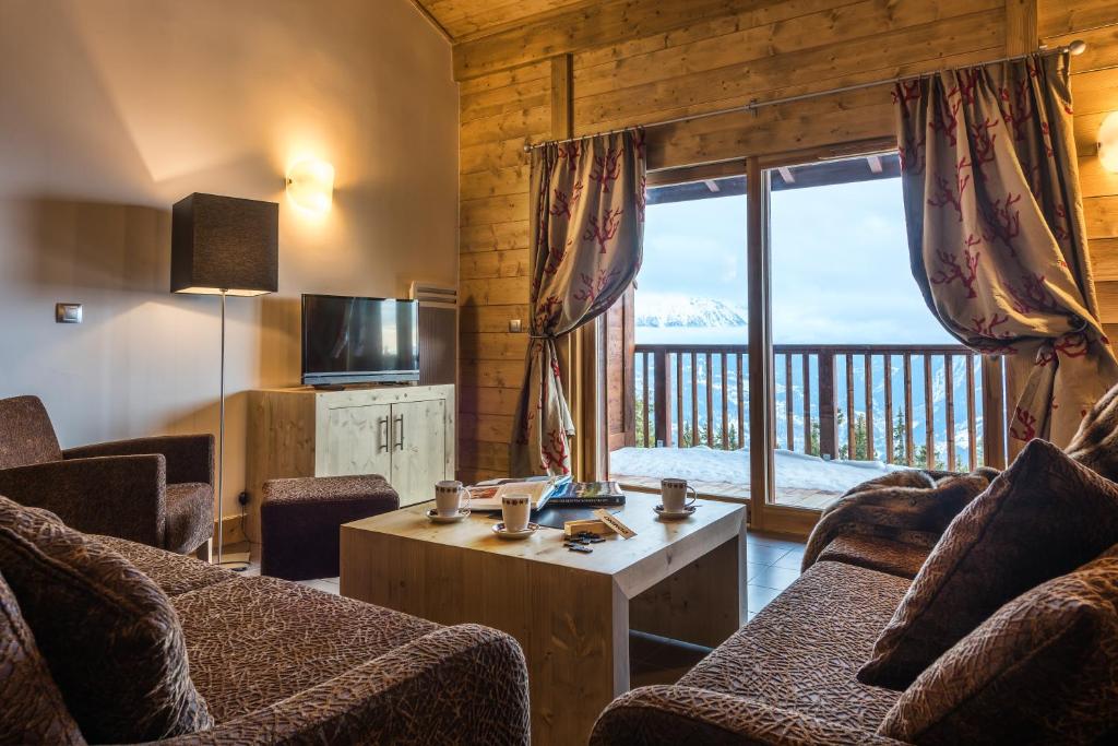 a living room with two couches and a large window at CGH Résidences &amp; Spas Chalet Les Marmottons in La Rosière