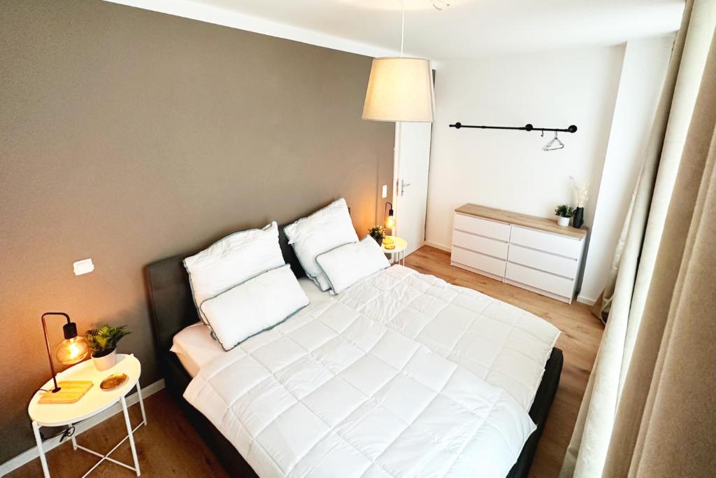 a bedroom with a large white bed and a table at Modernes City-Apartment in Mönchengladbach in Mönchengladbach